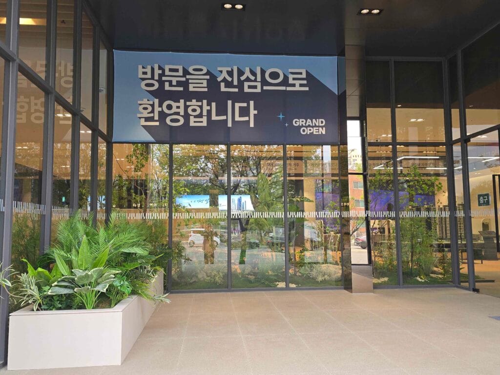 그랜드 오픈 현수막이 걸려 있는 더샵 오산역 아크시티 모델하우스 1층 입구 외관