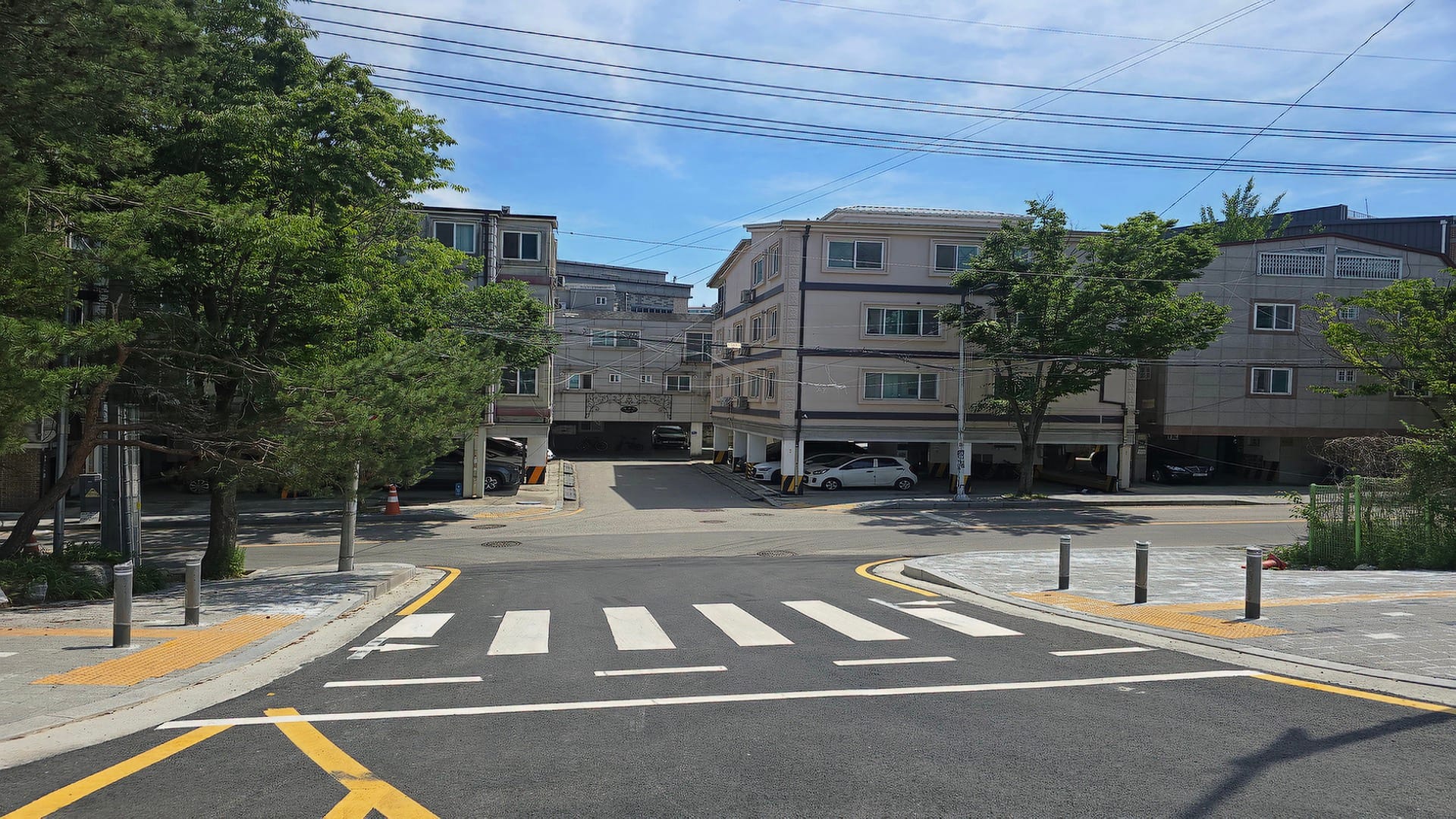북수원 이목지구 디에트르 단지 전면부 도로 및 주변 주거지 전경으로 왕복 도로와 횡단보도가 전면에 위치하고 저층 주택가와 가로수가 평탄하게 펼쳐진 일부 동의 조망 환경