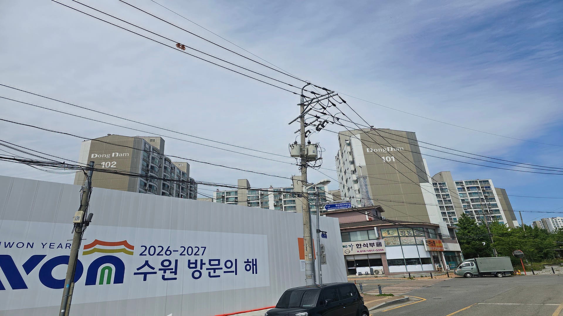 수원역 아너스빌 타임원 사업 부지 바로 맞은편으로 밀집한 노후 기축 단지인 동남아파트 건물과 주변 전신주 전경